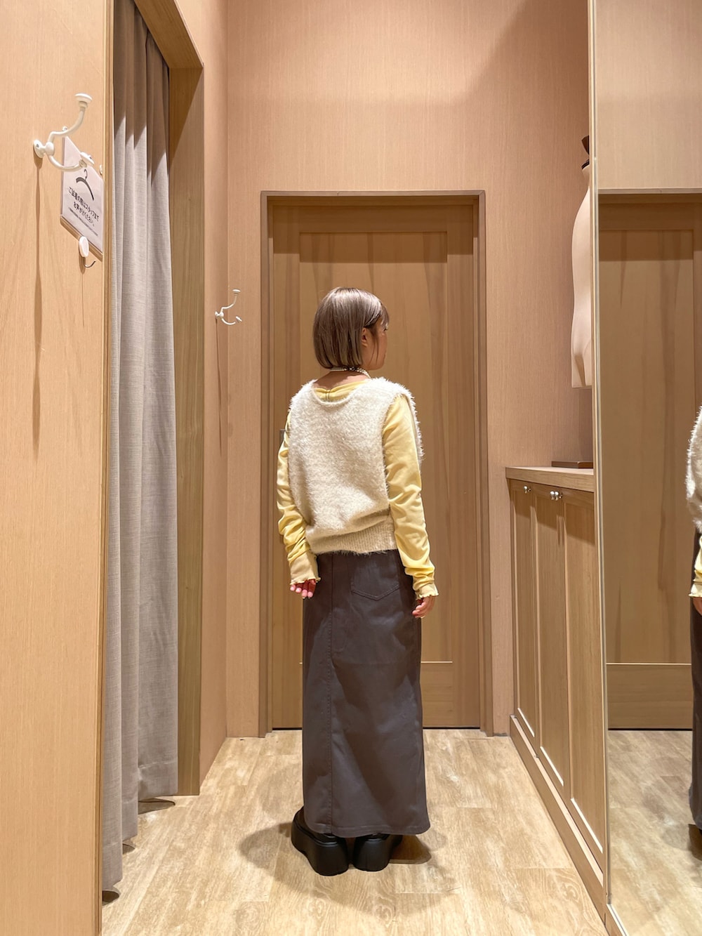 ブラック系のブーツ、グレー系のスカート、ホワイト系のベストを着用したレディースの秋コーディネートの3枚目の写真