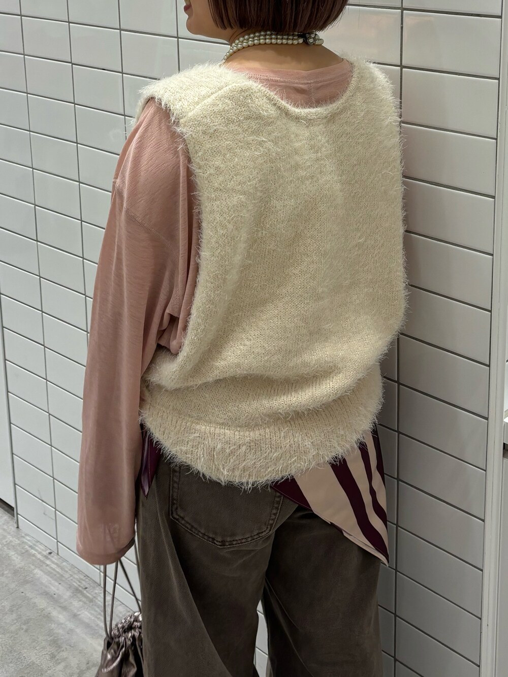 ホワイト系のベスト、ブラウン系のデニムパンツ、ベージュ系のトートバッグを着用したレディースの秋コーディネートの4枚目の写真