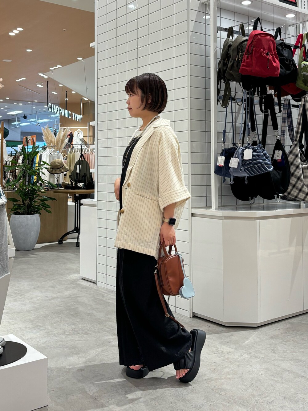 ブラック系のサロペット/オーバーオール、ホワイト系のテーラードジャケット、ブラック系のサンダルを着用したレディースの夏コーディネートの3枚目の写真