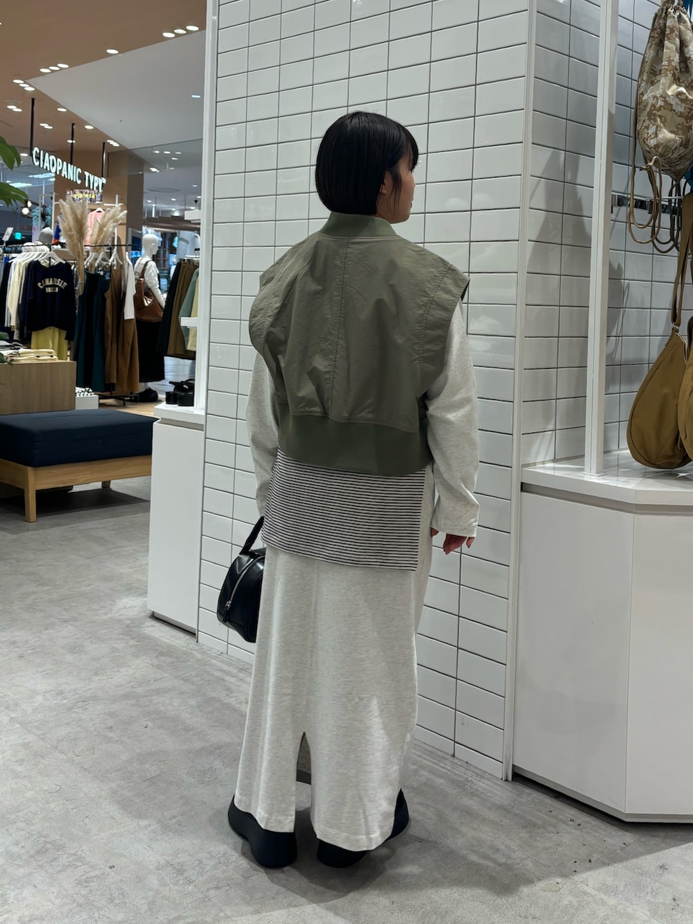 グリーン系のベスト、ブラック系のショルダーバッグ、ブラック系のサンダルを着用したレディースの春コーディネートの3枚目の写真