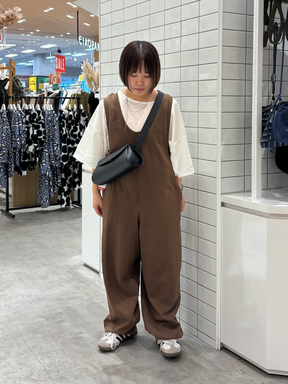 ブラウン系のサロペット/オーバーオール、ホワイト系のTシャツ/カットソー、ブラック系のショルダーバッグを着用したレディースの夏コーディネートの2枚目の写真