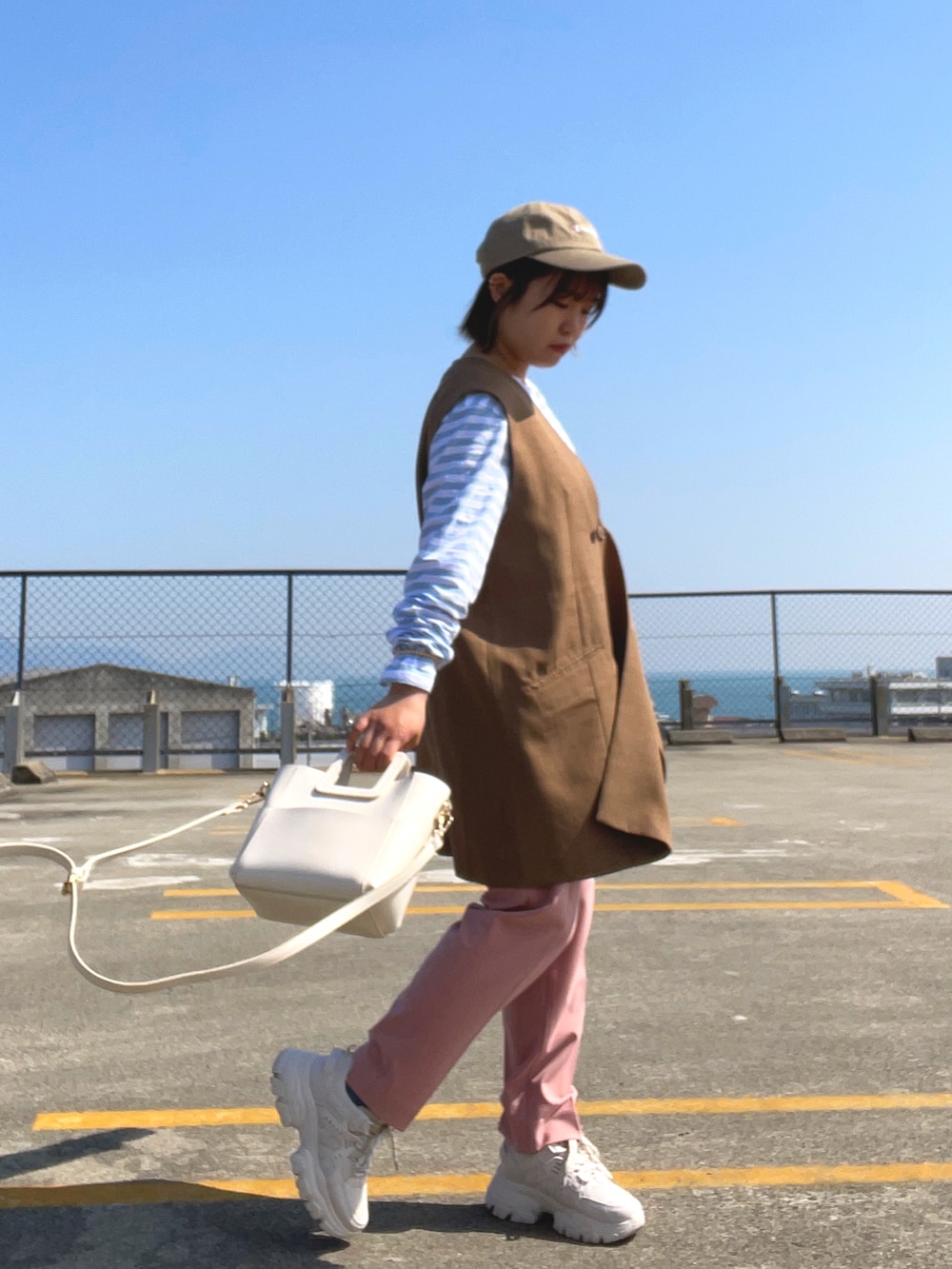 ブルー系のTシャツ/カットソー、ブラウン系のベスト、ホワイト系のショルダーバッグを着用したレディースの春コーディネートの2枚目の写真