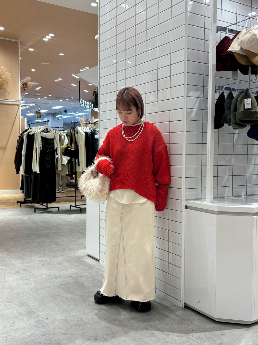 レッド系のニット/セーター、ホワイト系のTシャツ/カットソー、ホワイト系のデニムスカートを着用したレディースの秋コーディネートの3枚目の写真