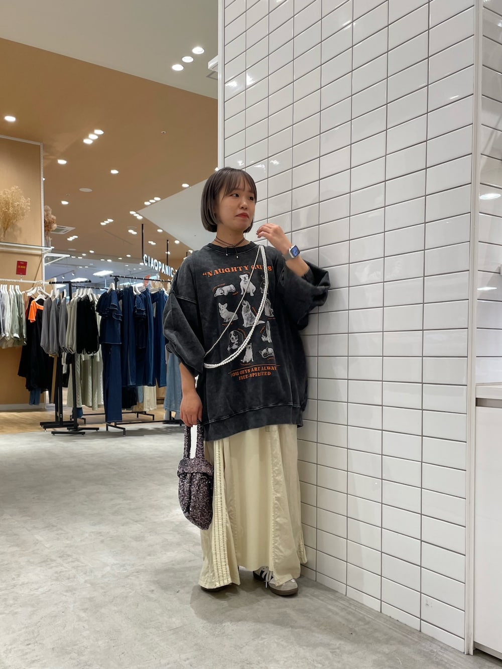 グレー系のハンドバッグ、ホワイト系のスカート、ブラック系のスウェットを着用したレディースの秋コーディネートの4枚目の写真