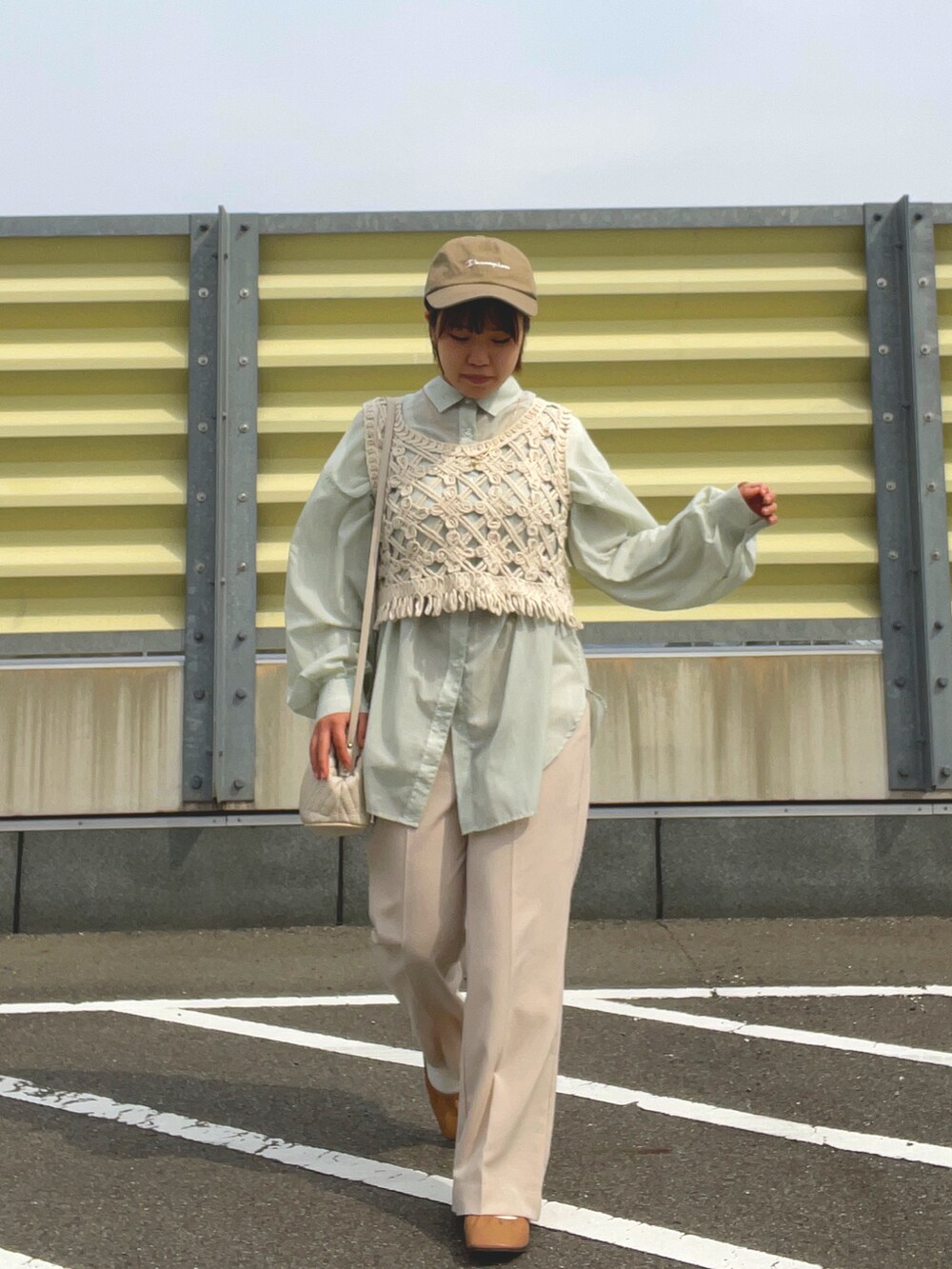ベージュ系のスラックス、ベージュ系のベスト、ホワイト系のショルダーバッグを着用したレディースの春コーディネートの4枚目の写真