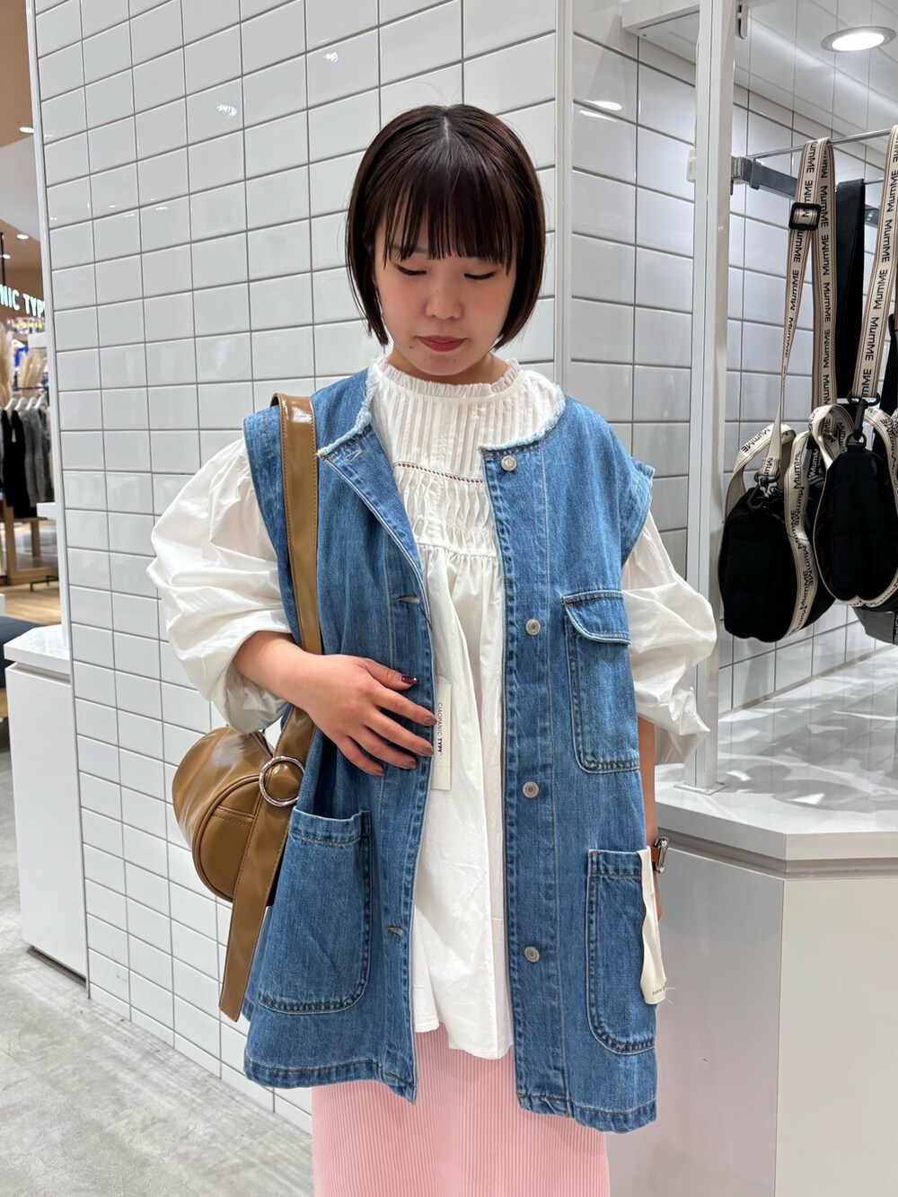 ブルー系のデニムジャケット、ベージュ系のショルダーバッグ、ホワイト系のシャツ/ブラウスを着用したレディースの春コーディネートの3枚目の写真
