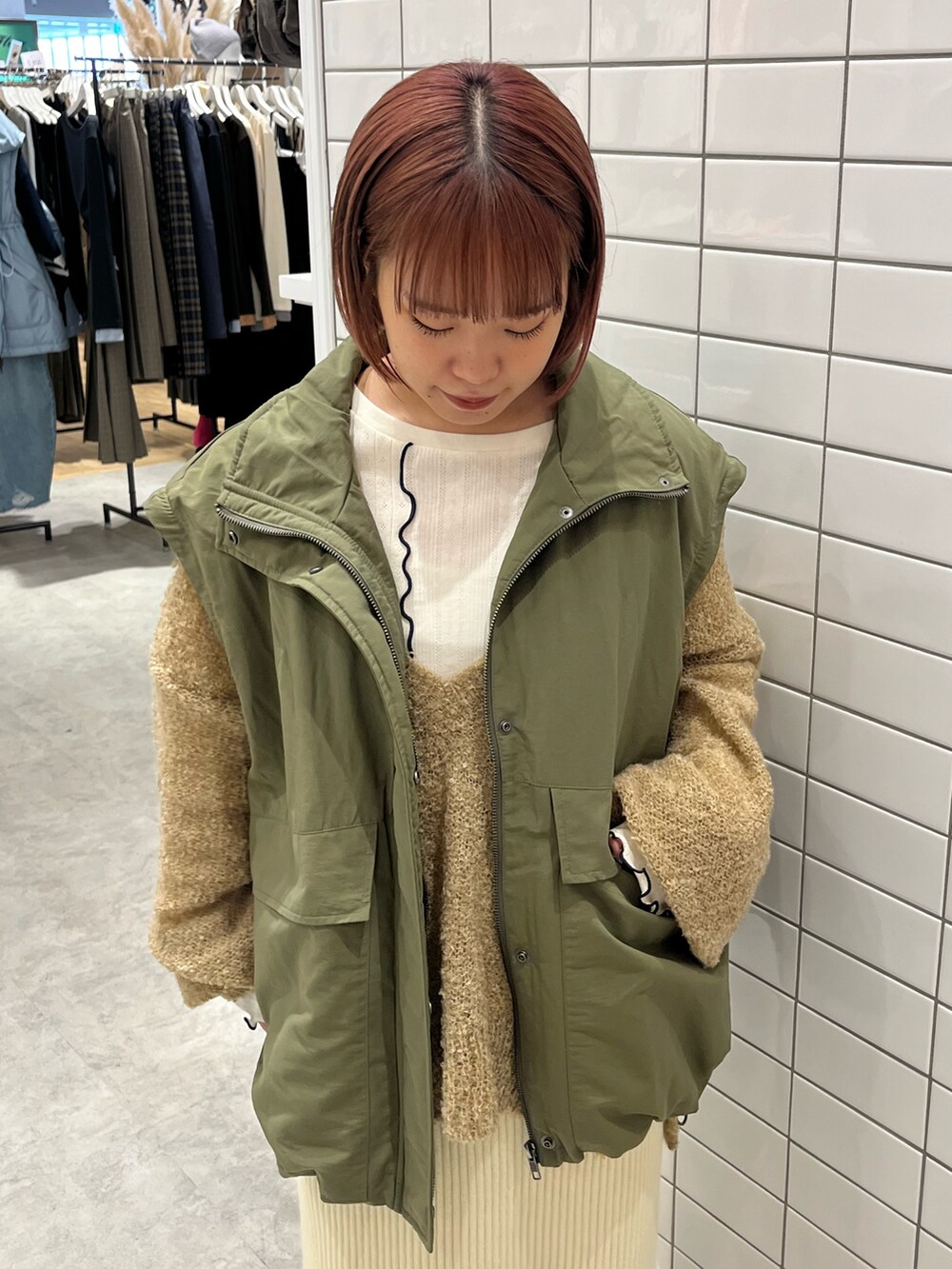 グリーン系のブルゾン、ホワイト系のスカート、ブラック系のブーツを着用したレディースの秋コーディネートの3枚目の写真