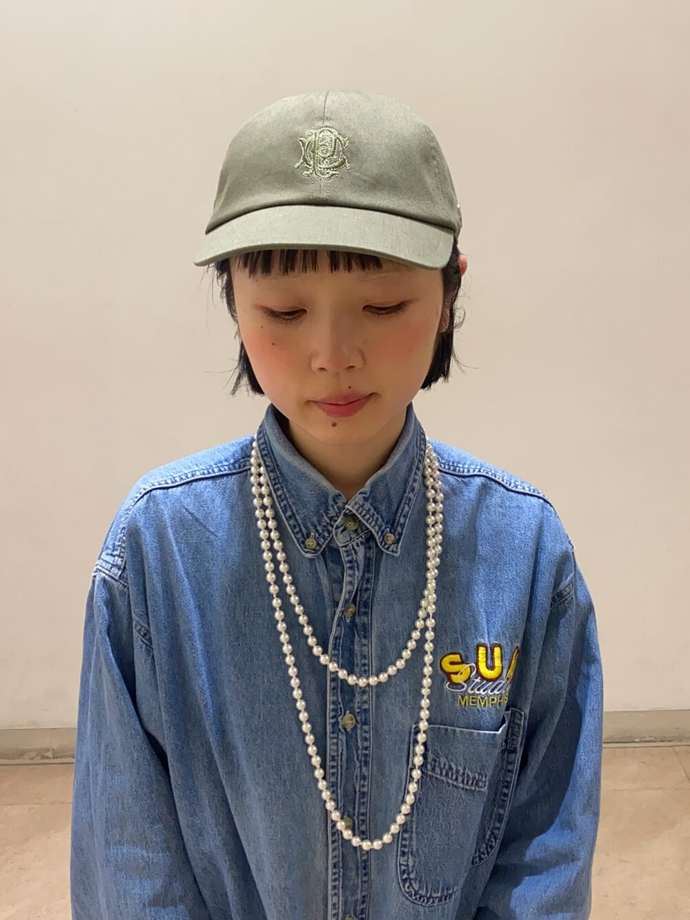 グリーン系のキャップを着用したレディースの春コーディネートの2枚目の写真