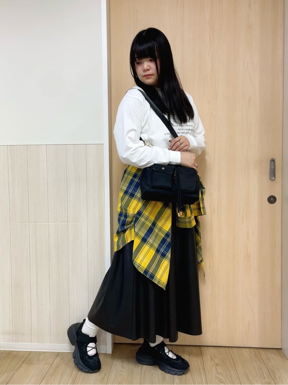 ホワイト系のTシャツ/カットソー、イエロー系のシャツ/ブラウス、ブラック系のスカートを着用したレディースの秋コーディネートの2枚目の写真