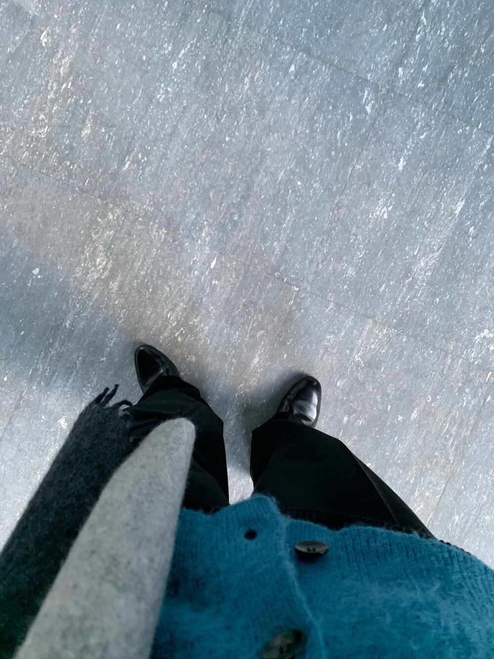 ブラック系のスラックス、ブラック系のスリッポン、ブルー系のカーディガン/ボレロを着用したメンズの冬コーディネートの2枚目の写真