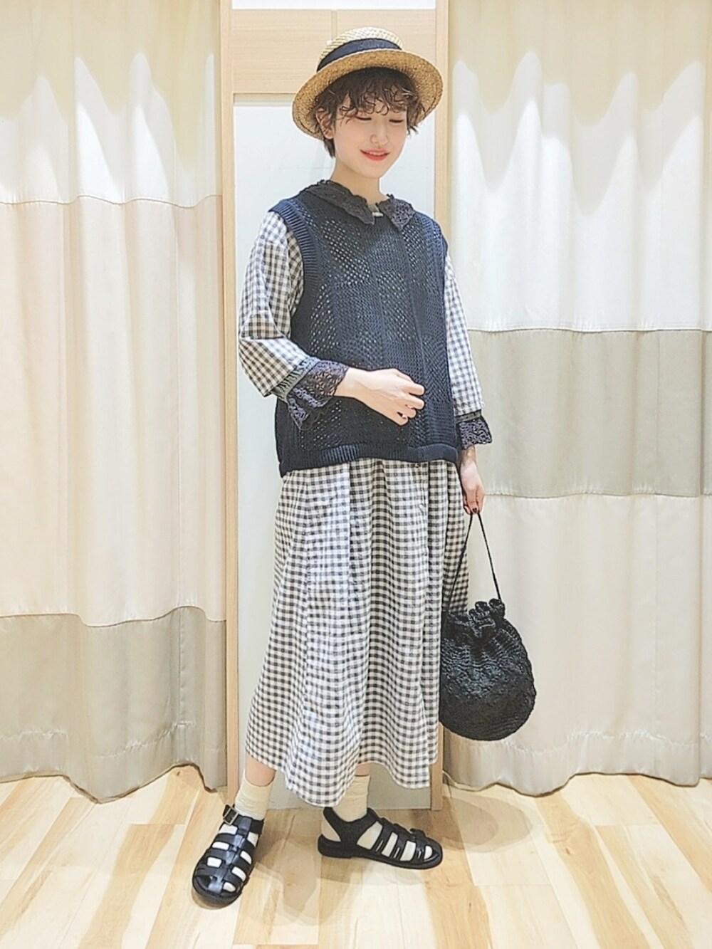 グレー系のベスト、グレー系のワンピース、ブラック系のシャツ/ブラウスを着用したレディースの春コーディネートの2枚目の写真