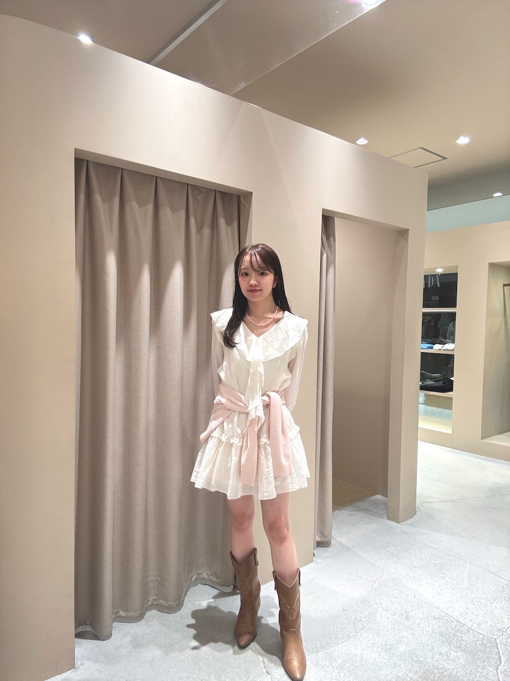 イエロー系のブーツ、ホワイト系のワンピース、ピンク系のカーディガン/ボレロを着用したレディースの春コーディネートの2枚目の写真