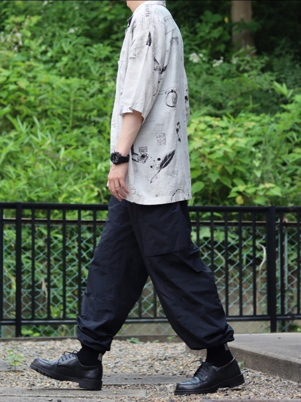 ブラック系のカーゴパンツ、ブラック系のドレスシューズ、ホワイト系のシャツ/ブラウスを着用したメンズの夏コーディネートの2枚目の写真