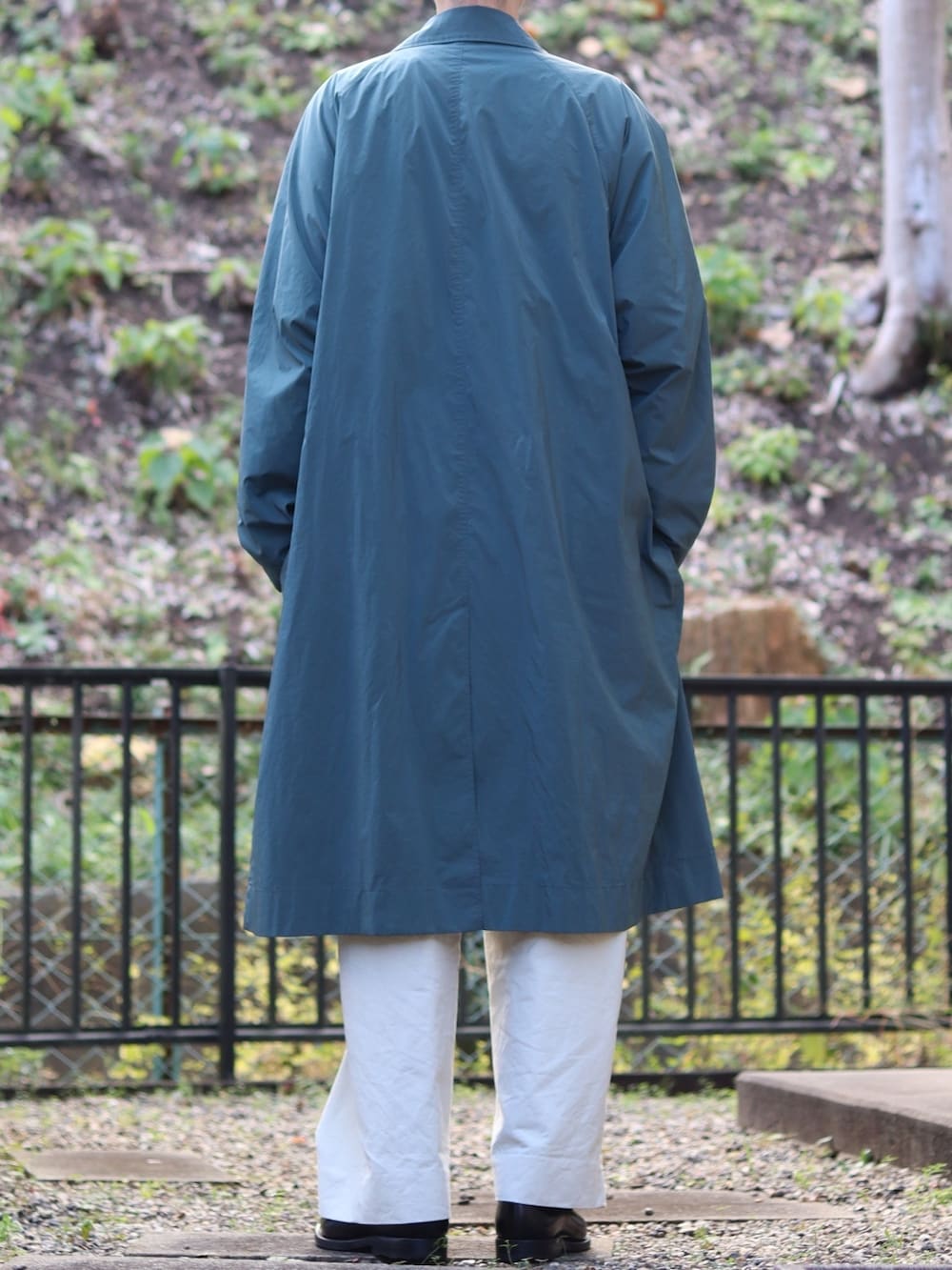 グレー系のニット/セーター、グリーン系のチェスターコート、ブラック系のショルダーバッグを着用したメンズの冬コーディネートの3枚目の写真