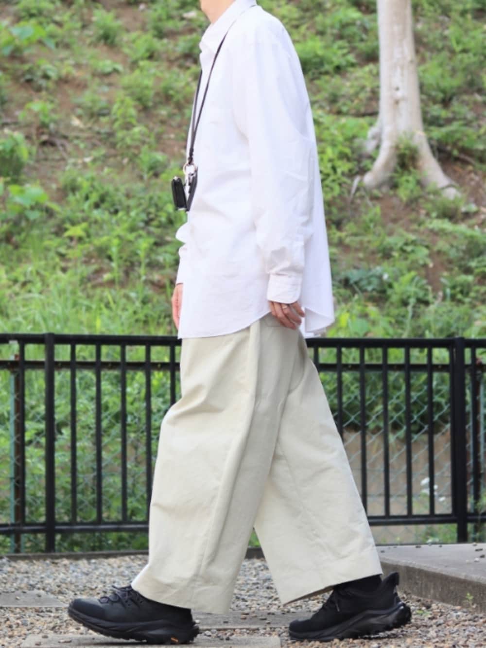 ホワイト系のパンツ、ブラック系のスニーカー、ブラック系のネックレスを着用したメンズの春コーディネートの2枚目の写真