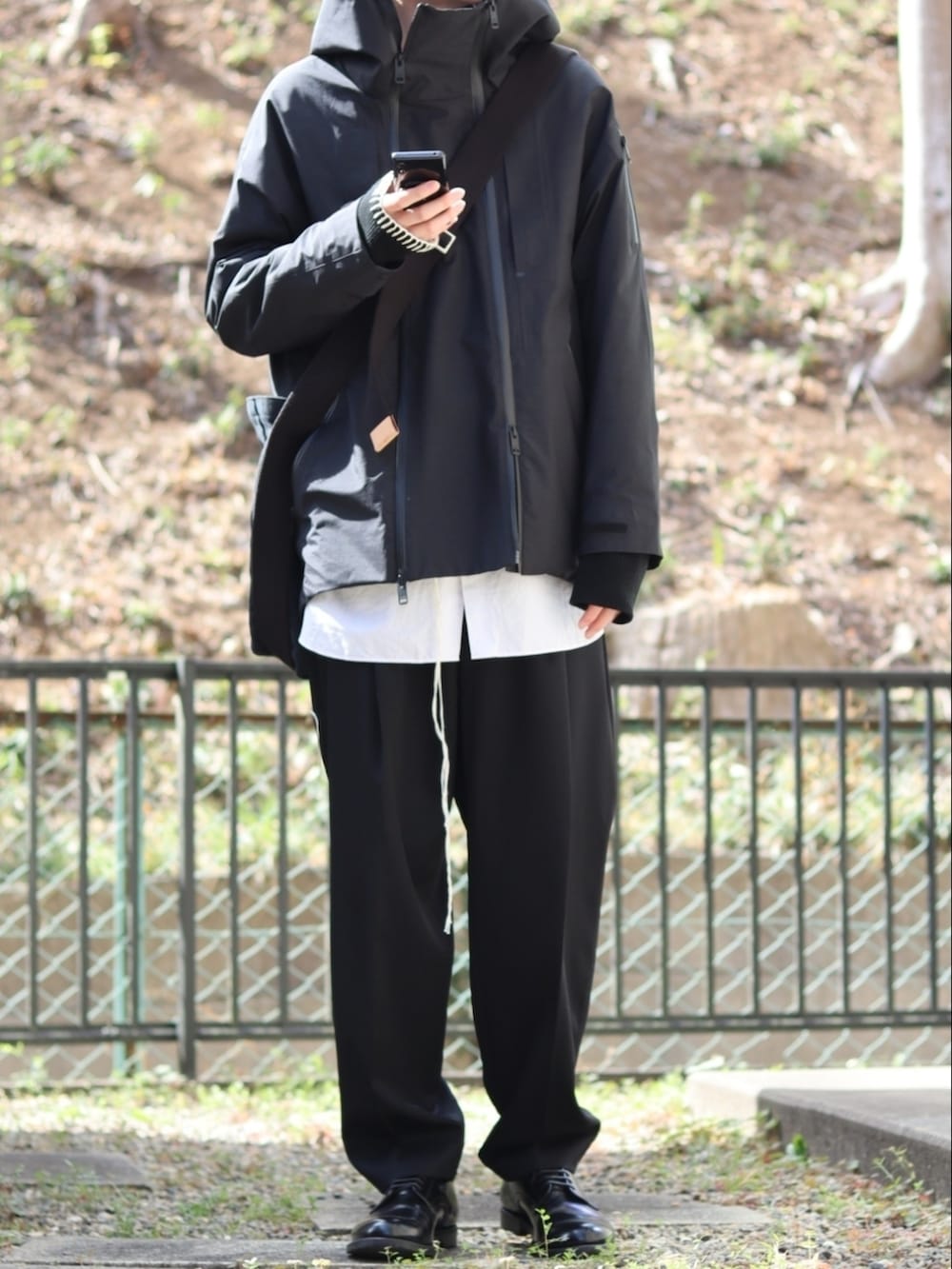 ブラック系のスラックス、ブラック系のドレスシューズ、ホワイト系のシャツ/ブラウスを着用したメンズの冬コーディネートの2枚目の写真