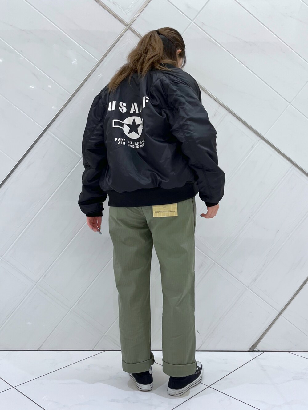 イエロー系のTシャツ/カットソー、グリーン系のその他パンツ、ブラック系のMA-1を着用したレディースの秋コーディネートの2枚目の写真