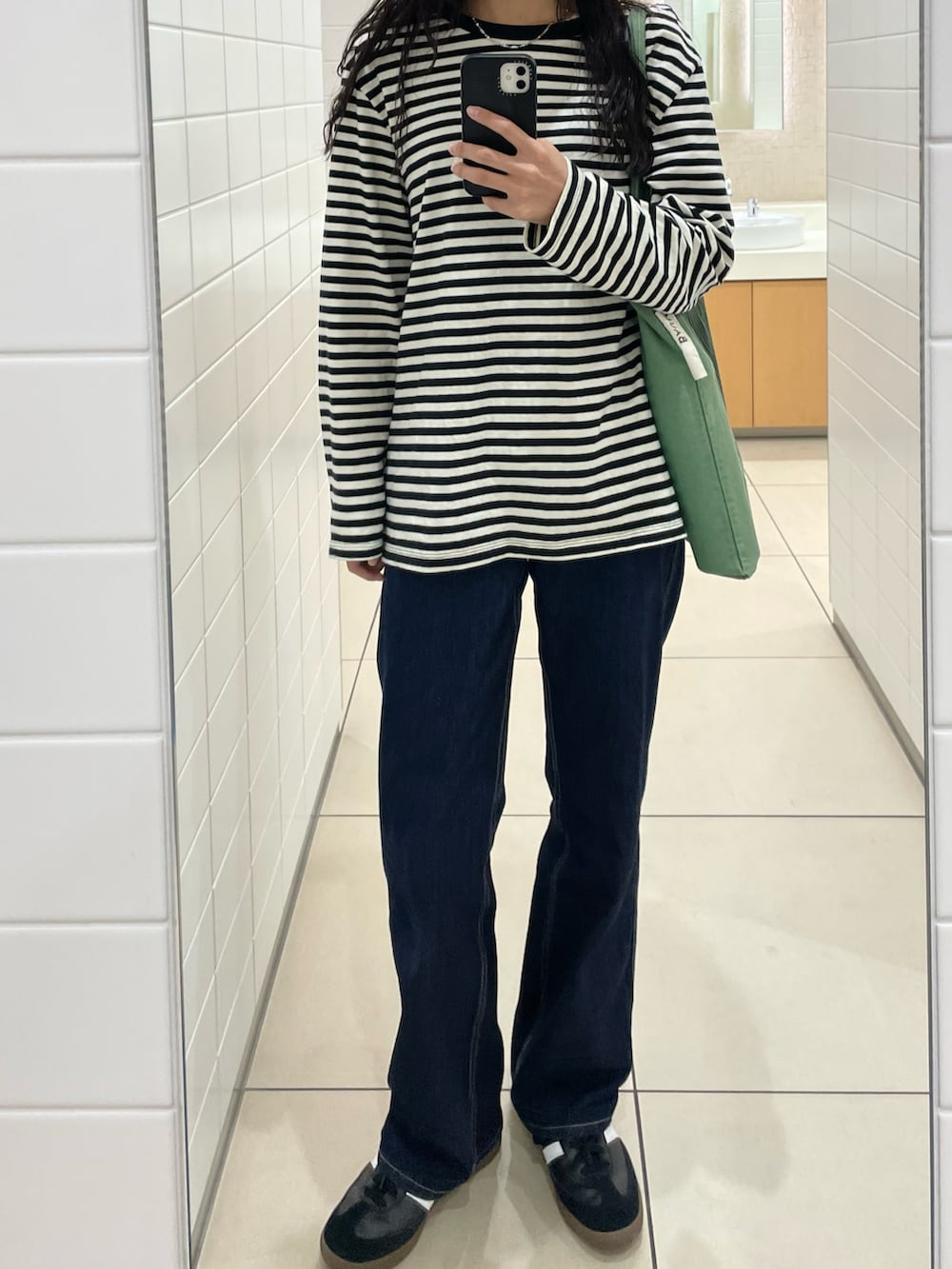 ホワイト系のTシャツ/カットソー、ブルー系のデニムパンツ、ブラック系のスニーカーを着用したレディースの秋コーディネートの2枚目の写真