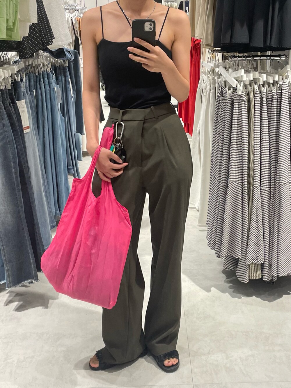 ブラック系のキャミソール、グリーン系のスラックス、ブラック系のサンダルを着用したレディースの夏コーディネートの2枚目の写真