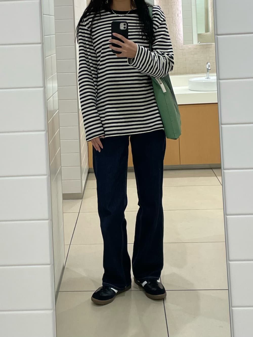 ホワイト系のTシャツ/カットソー、ブルー系のデニムパンツ、ブラック系のスニーカーを着用したレディースの秋コーディネートの3枚目の写真