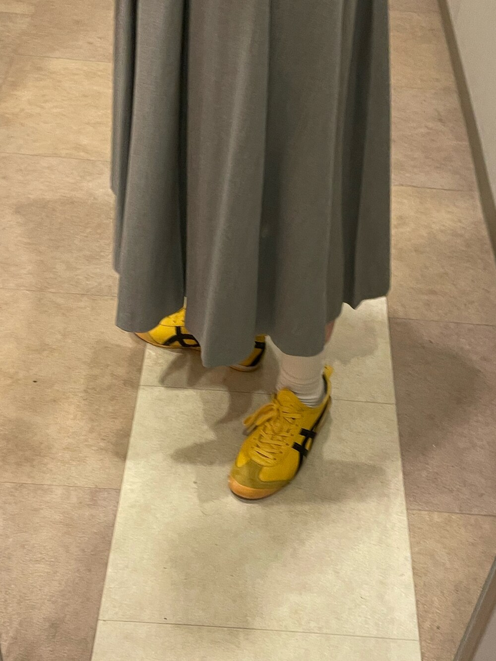 ブラック系のTシャツ/カットソー、グレー系のスカート、イエロー系のスニーカーを着用したレディースの秋コーディネートの3枚目の写真