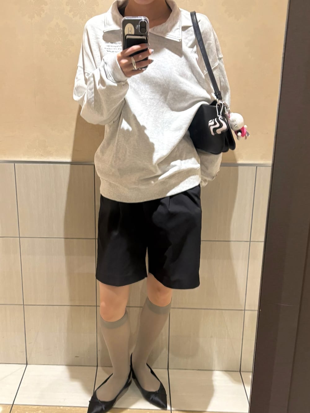 グレー系のスウェット、ブラック系のパンツ、ブラック系のドレスシューズを着用したレディースの秋コーディネートの2枚目の写真