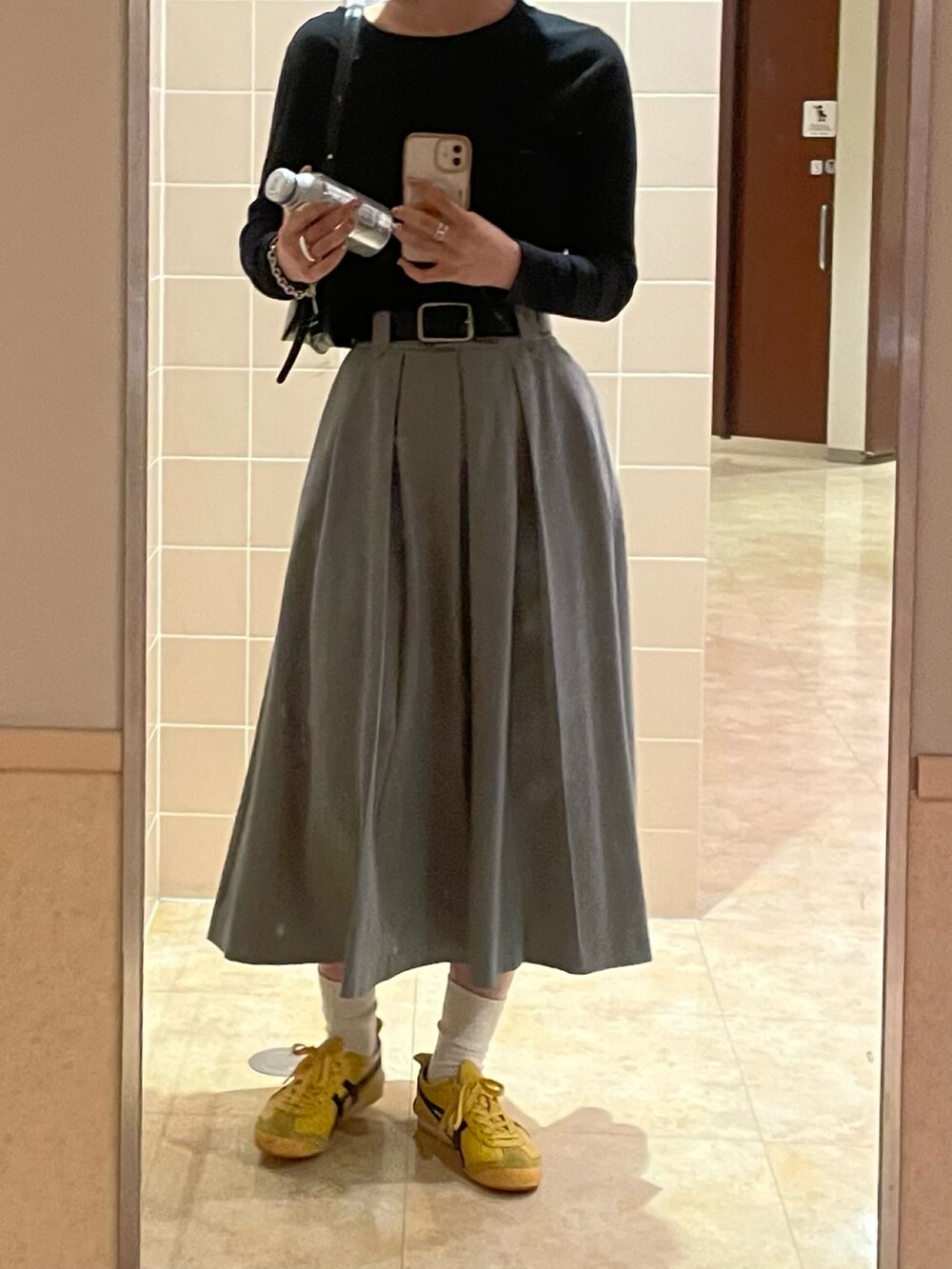 ブラック系のTシャツ/カットソー、グレー系のスカート、イエロー系のスニーカーを着用したレディースの秋コーディネートの2枚目の写真