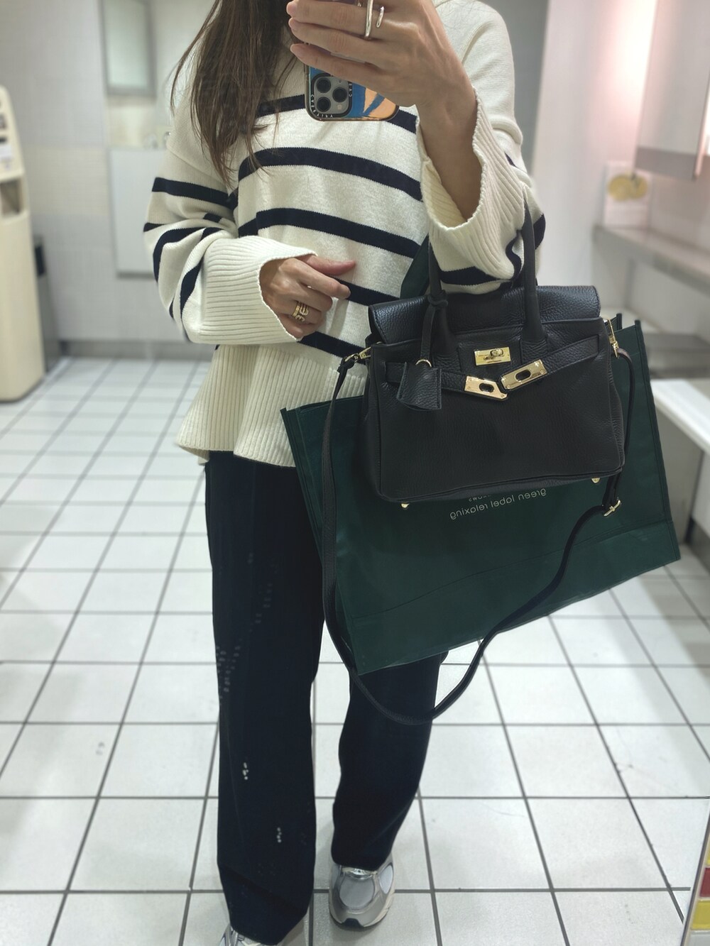 ブラック系のショルダーバッグ、ベージュ系のスニーカー、ゴールド系のピアス（両耳用）を着用したレディースの秋コーディネートの2枚目の写真