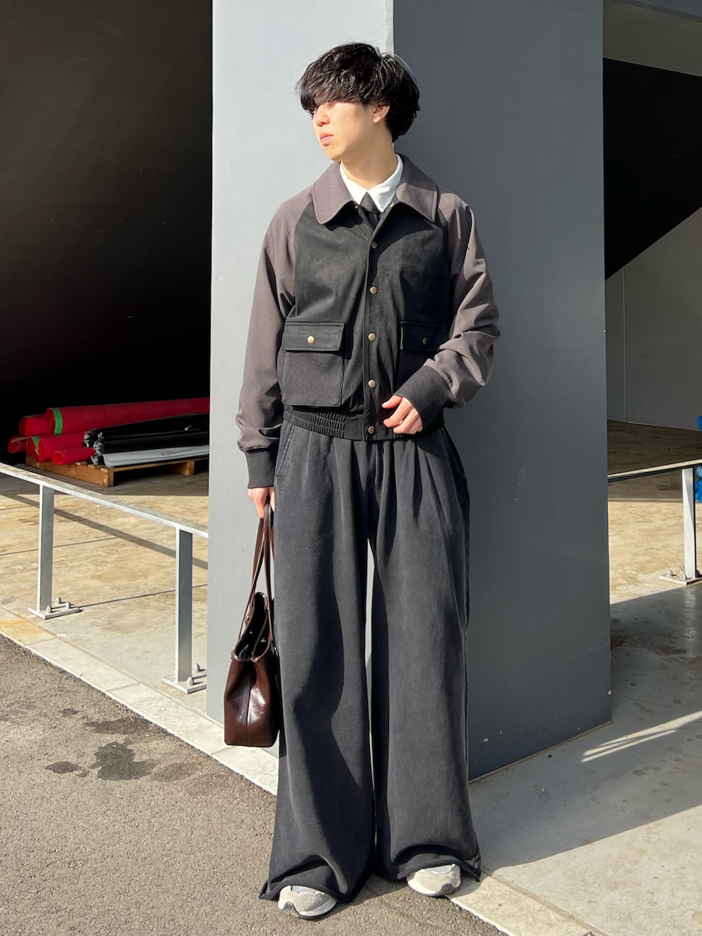 グレー系のスニーカー、ブラック系のスウェットパンツ、ブラウン系のハンドバッグを着用したメンズの春コーディネートの2枚目の写真