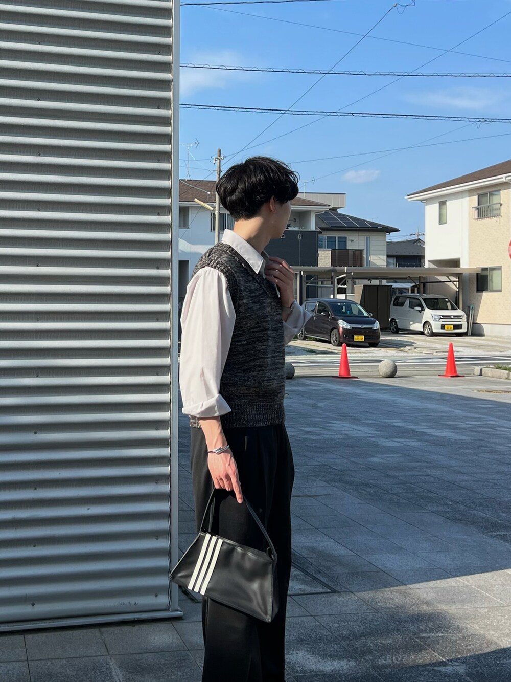 ブラック系のスラックス、ブラック系のローファー、ブラック系のハンドバッグを着用したメンズの春コーディネートの2枚目の写真