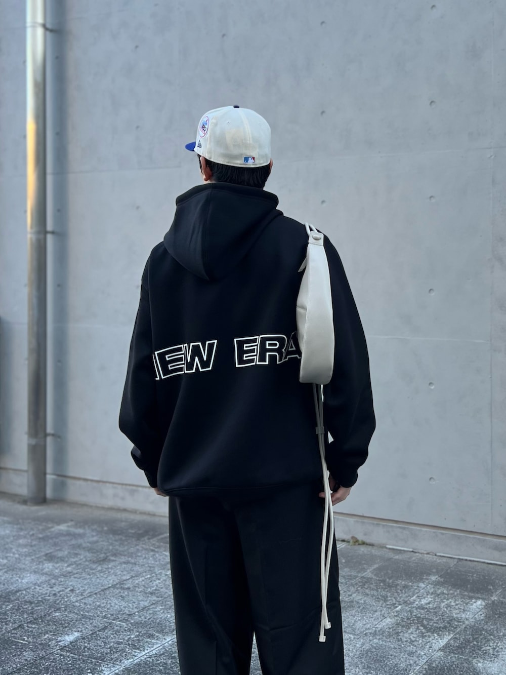 グレー系のショルダーバッグ、ブラック系のパーカー、ブラック系のスラックスを着用したメンズの秋コーディネートの2枚目の写真