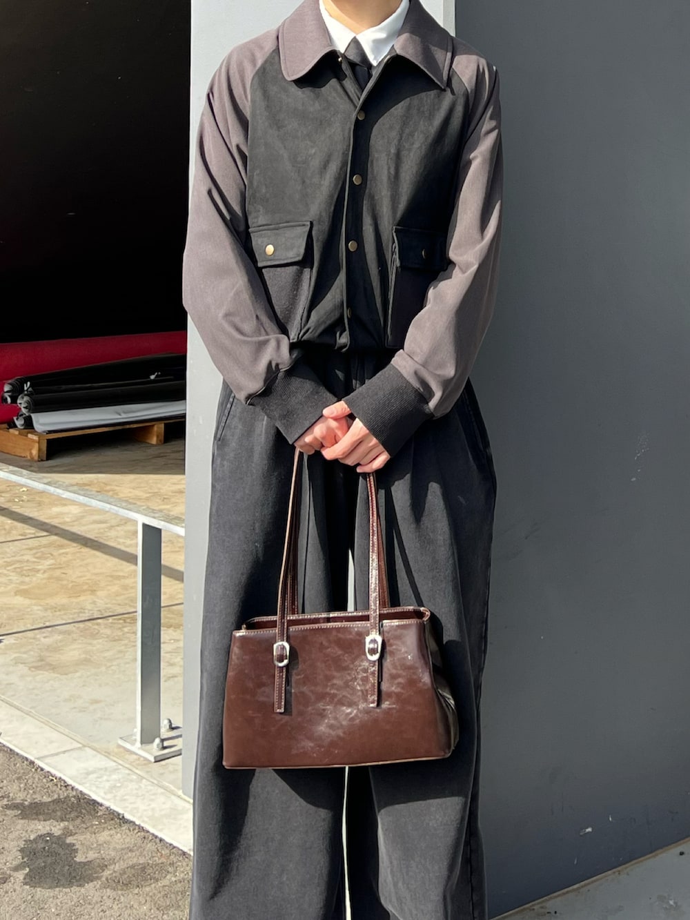 グレー系のスニーカー、ブラック系のスウェットパンツ、ブラウン系のハンドバッグを着用したメンズの春コーディネートの3枚目の写真