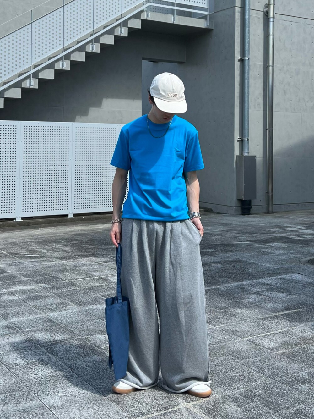 ブルー系のトートバッグ、グレー系のスウェットパンツ、ホワイト系のスニーカーを着用したメンズの夏コーディネートの2枚目の写真