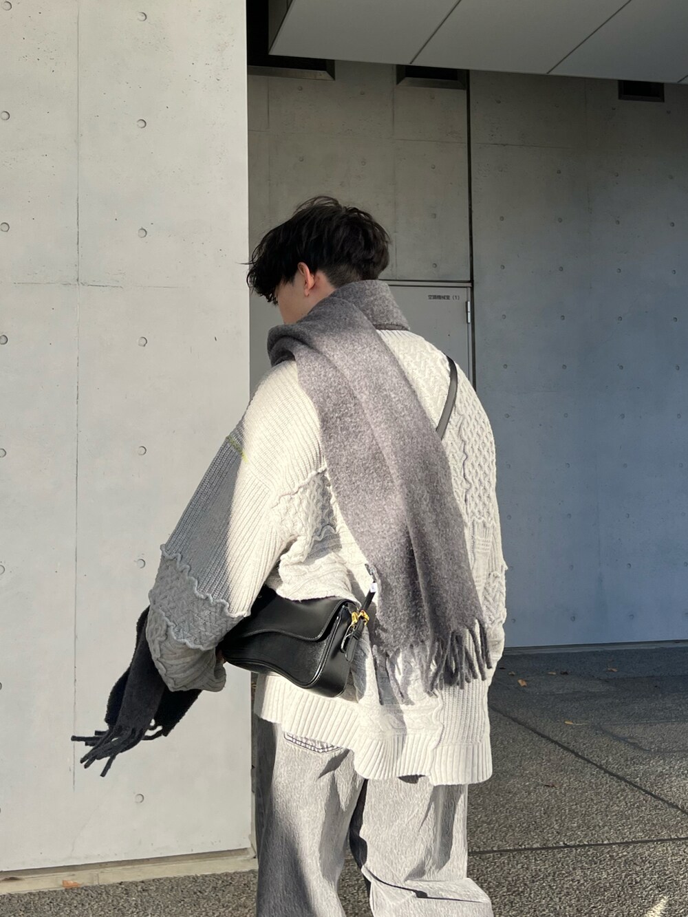 ベージュ系のニット/セーター、ブラック系のローファー、グレー系のデニムパンツを着用したメンズの冬コーディネートの2枚目の写真