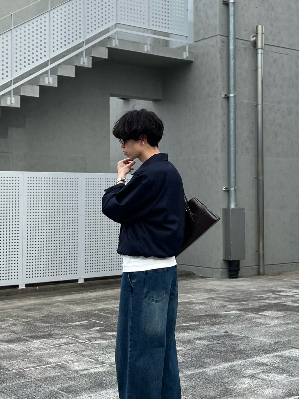 ブルー系のデニムパンツ、ブルー系のブルゾン、ブラウン系のハンドバッグを着用したメンズの春コーディネートの2枚目の写真