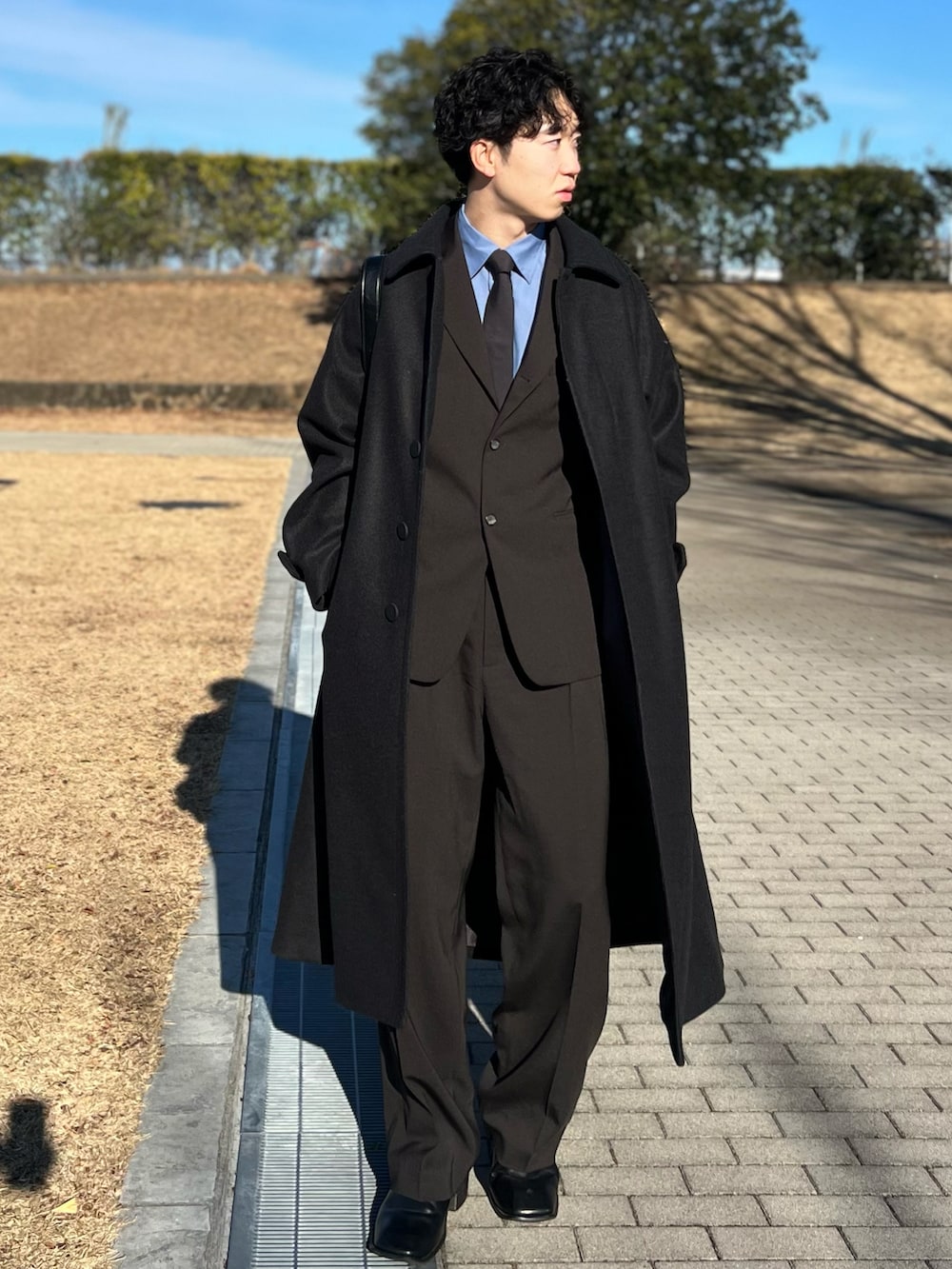 ブルー系のシャツ/ブラウス、ブラック系のステンカラーコート、グレー系のネクタイを着用したメンズの冬コーディネートの2枚目の写真