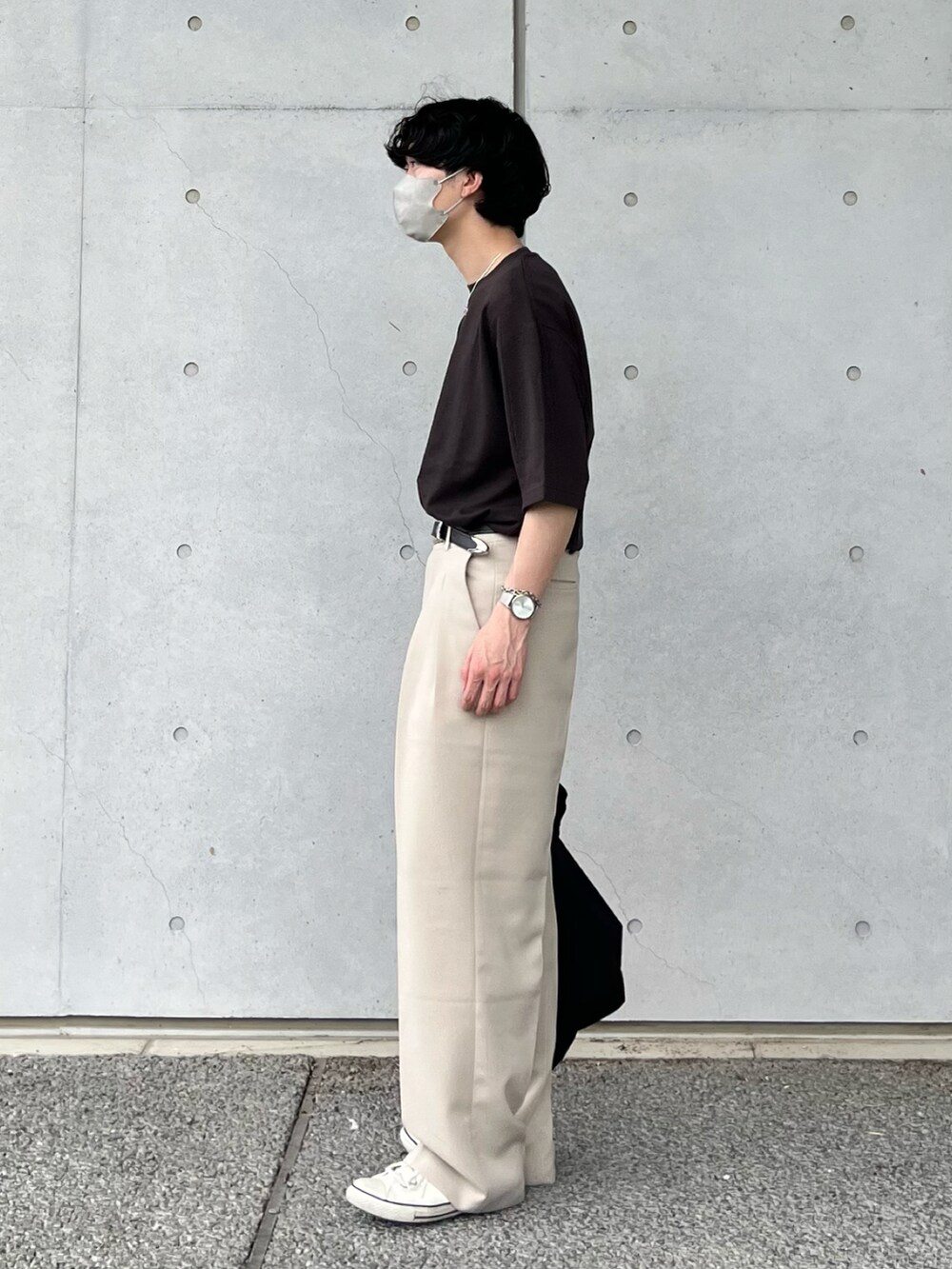 ブラック系のTシャツ/カットソー、ベージュ系のスラックス、ホワイト系のスニーカーを着用したメンズの夏コーディネートの2枚目の写真