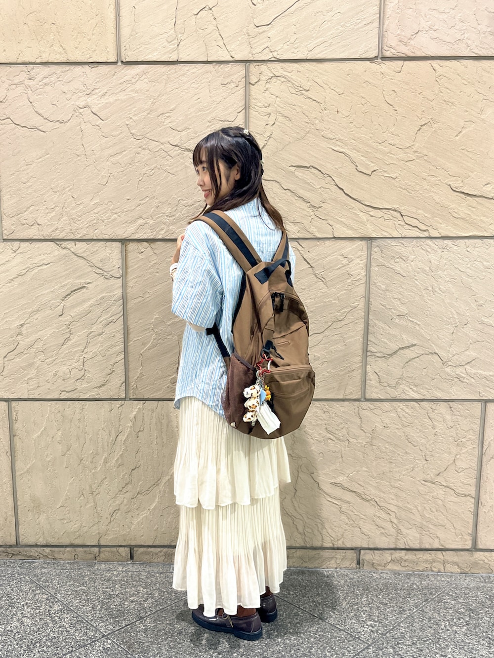 ホワイト系のスカート、ブラウン系のローファー、ブラウン系のバックパック/リュックを着用したレディースの秋コーディネートの2枚目の写真