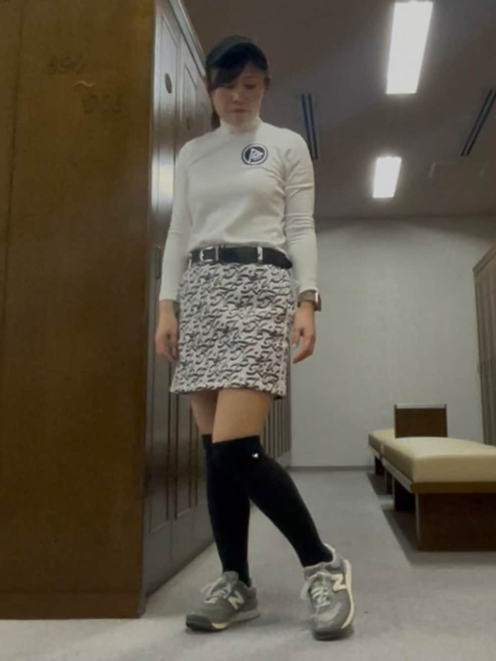 グレー系のスカート、グリーン系のベスト、ブラック系のサンバイザーを着用したレディースの春コーディネートの4枚目の写真