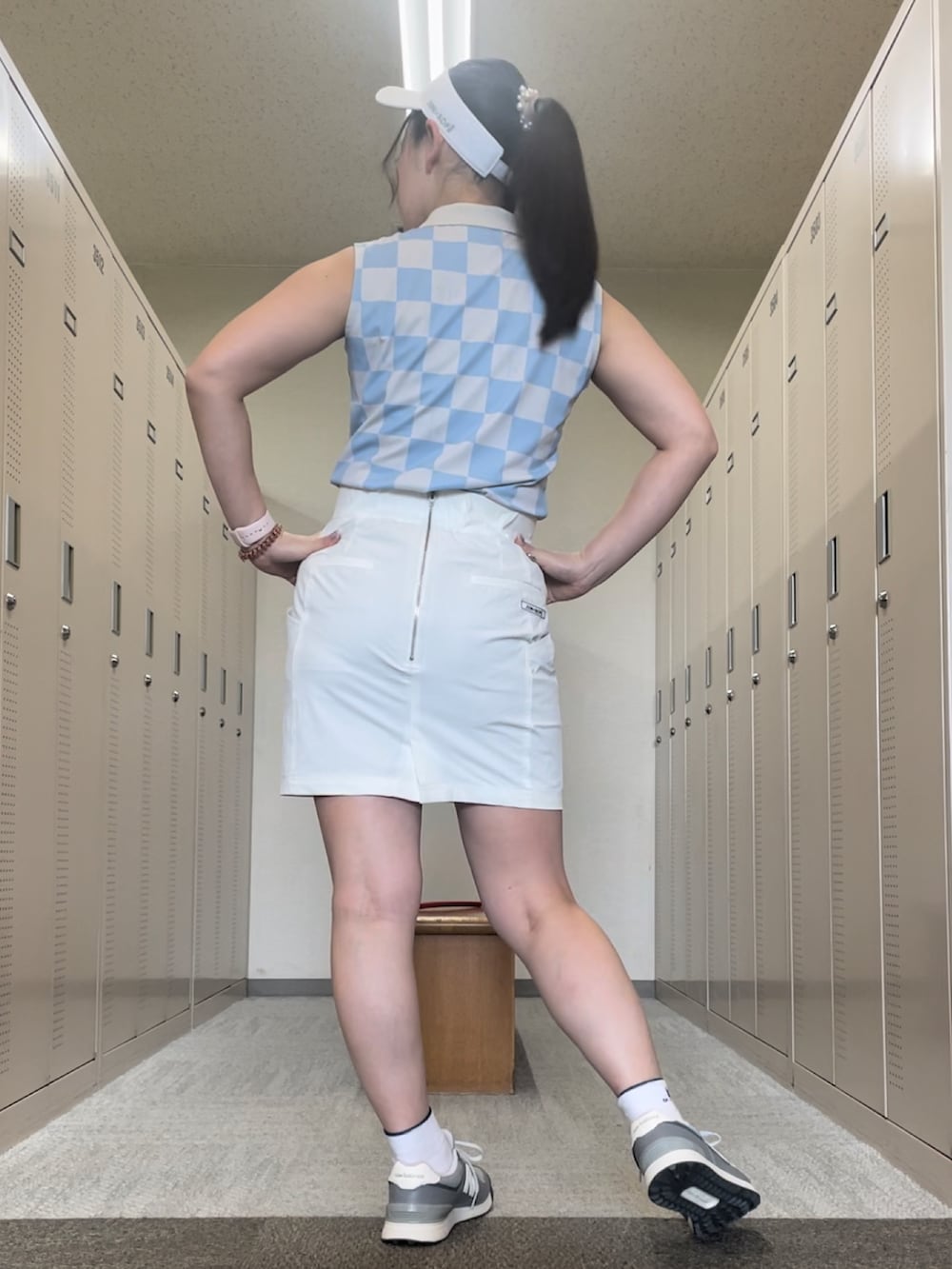 ホワイト系のスカート、グレー系のスニーカー、ブルー系のポロシャツを着用したレディースの夏コーディネートの2枚目の写真