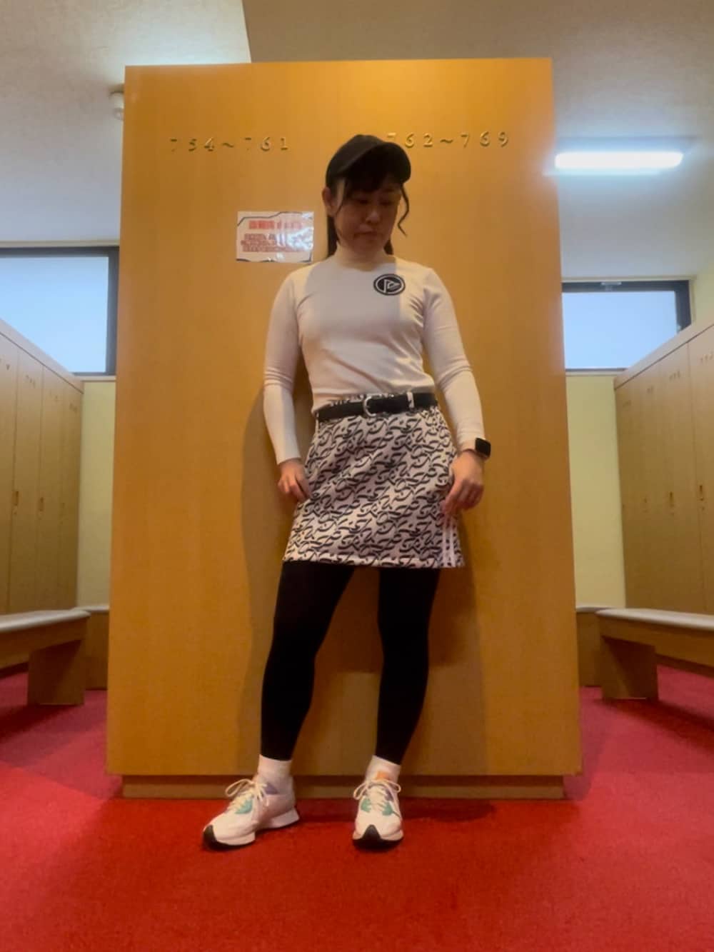 グレー系のスカート、ホワイト系のトップス、ホワイト系のスニーカーを着用したレディースの春コーディネートの2枚目の写真