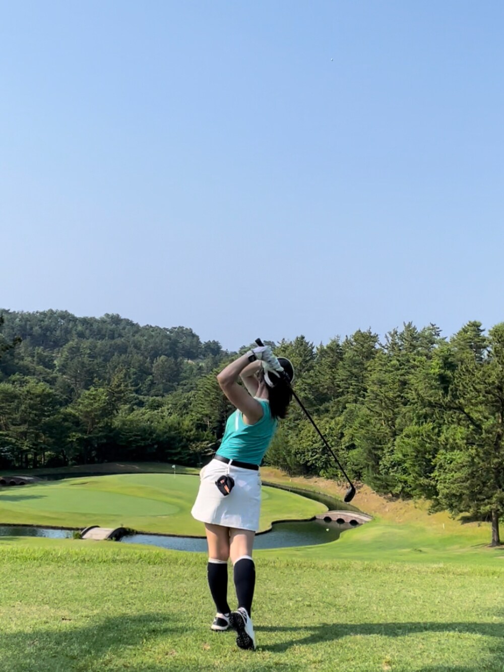 グリーン系のTシャツ/カットソー、ホワイト系のスカート、ホワイト系のスニーカーを着用したレディースの夏コーディネートの3枚目の写真