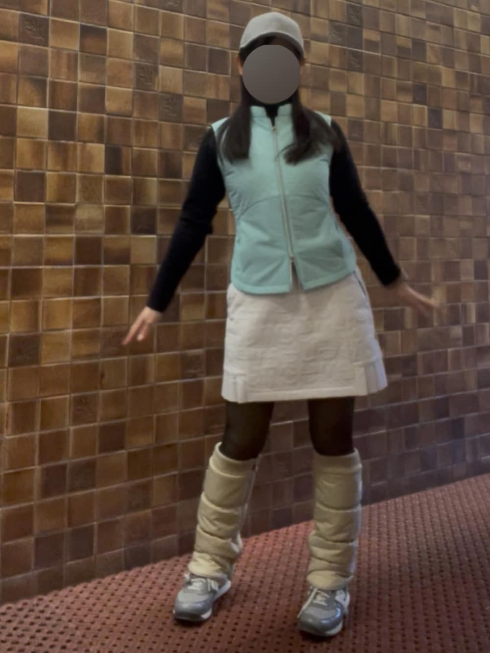 グリーン系のベスト、ホワイト系のスカート、シルバー系のキャップを着用したレディースの春コーディネートの3枚目の写真