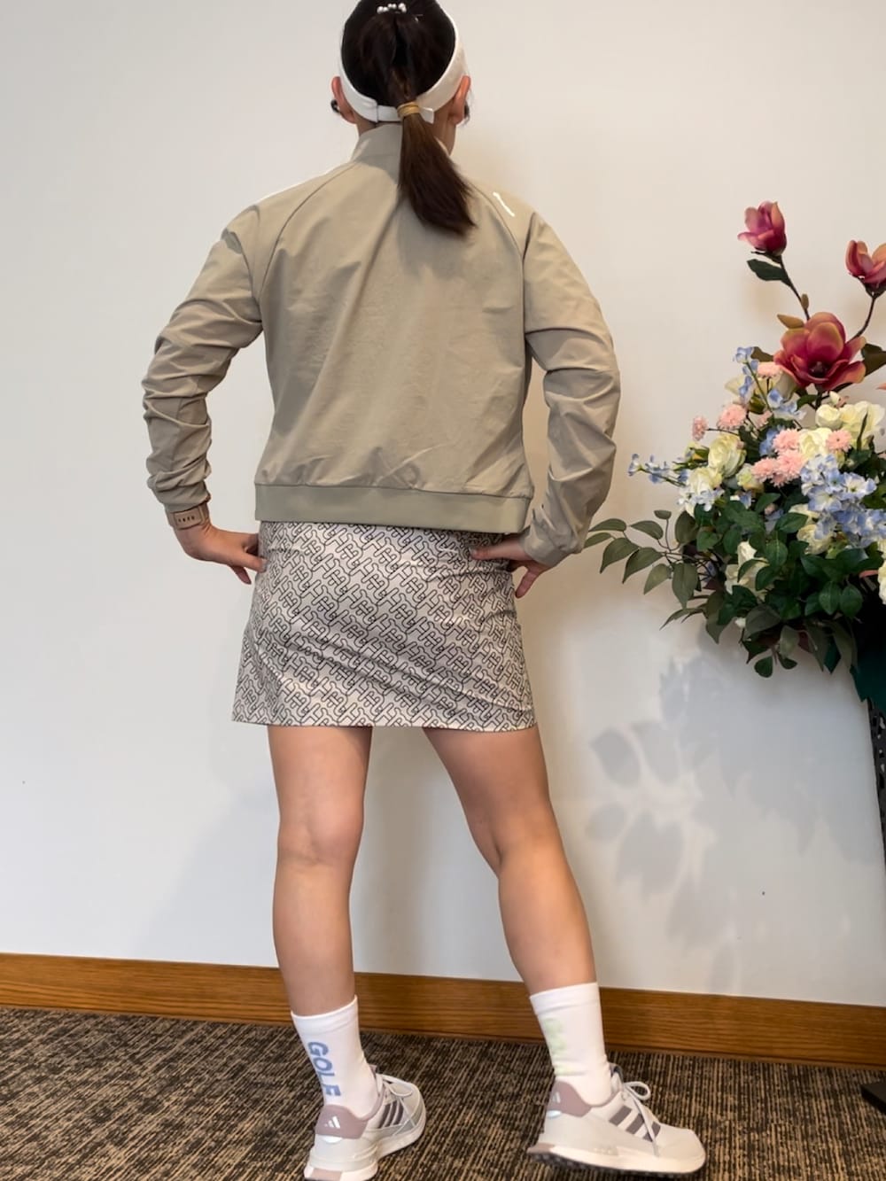 ベージュ系のポロシャツ、ベージュ系のスカート、ホワイト系のスニーカーを着用したレディースの秋コーディネートの4枚目の写真