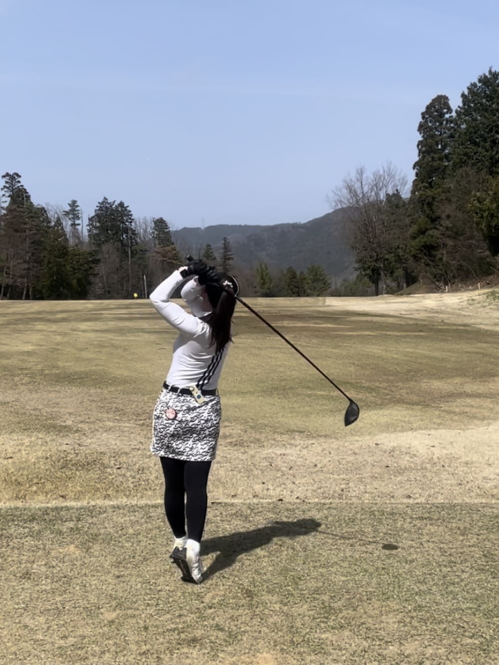 グレー系のスカート、ホワイト系のトップス、ホワイト系のスニーカーを着用したレディースの春コーディネートの5枚目の写真