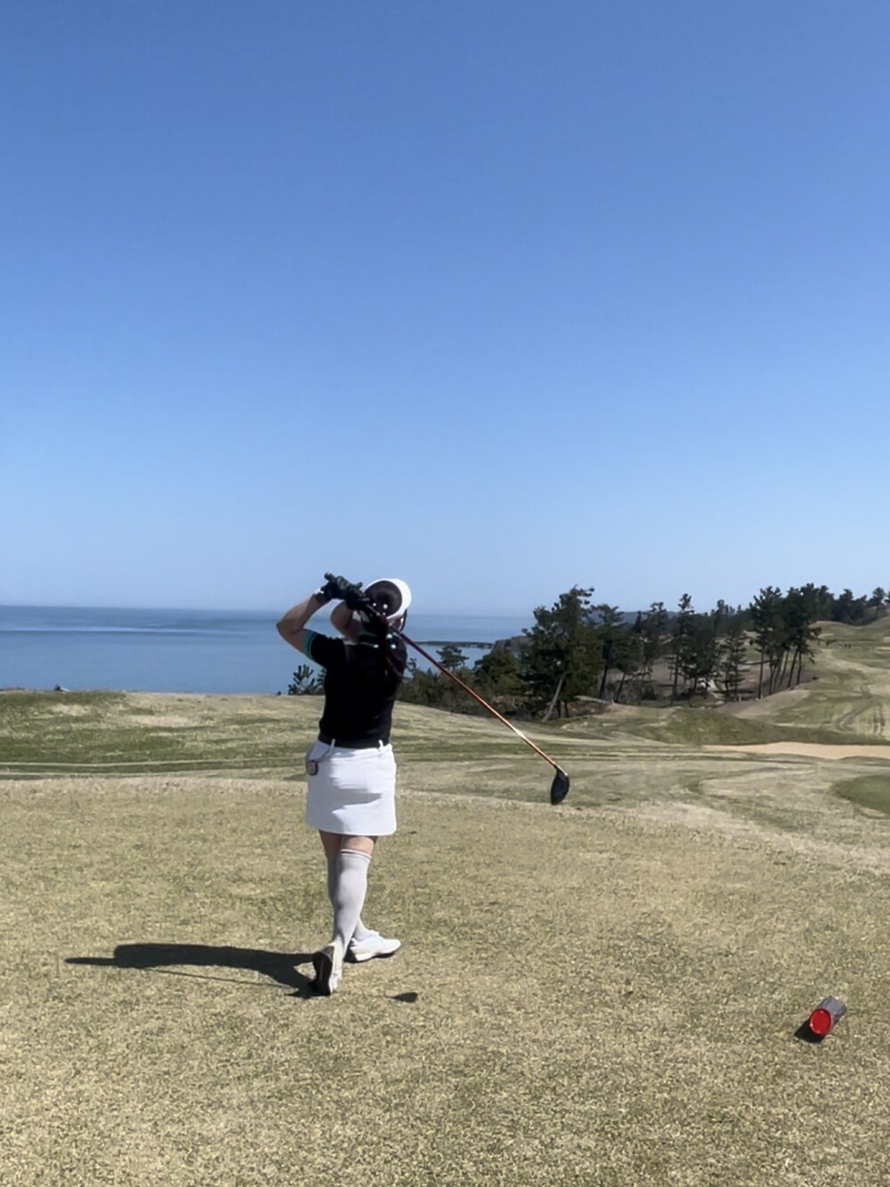 ブラック系のニット/セーター、ホワイト系のスカート、ホワイト系のスニーカーを着用したレディースの春コーディネートの4枚目の写真