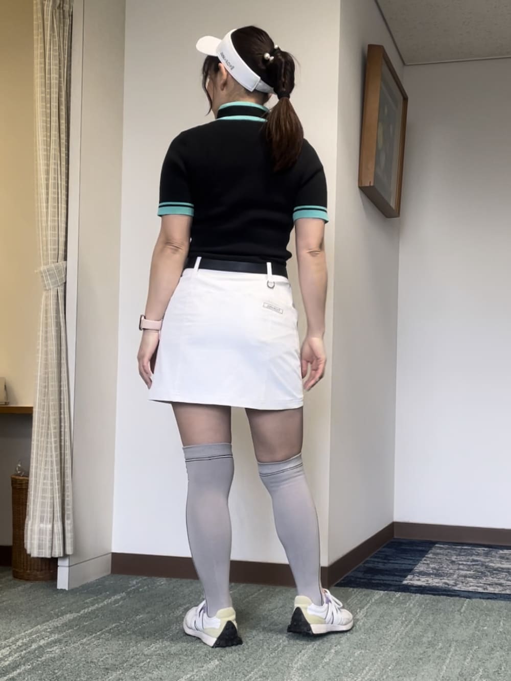 ブラック系のニット/セーター、ホワイト系のスカート、ホワイト系のスニーカーを着用したレディースの春コーディネートの2枚目の写真