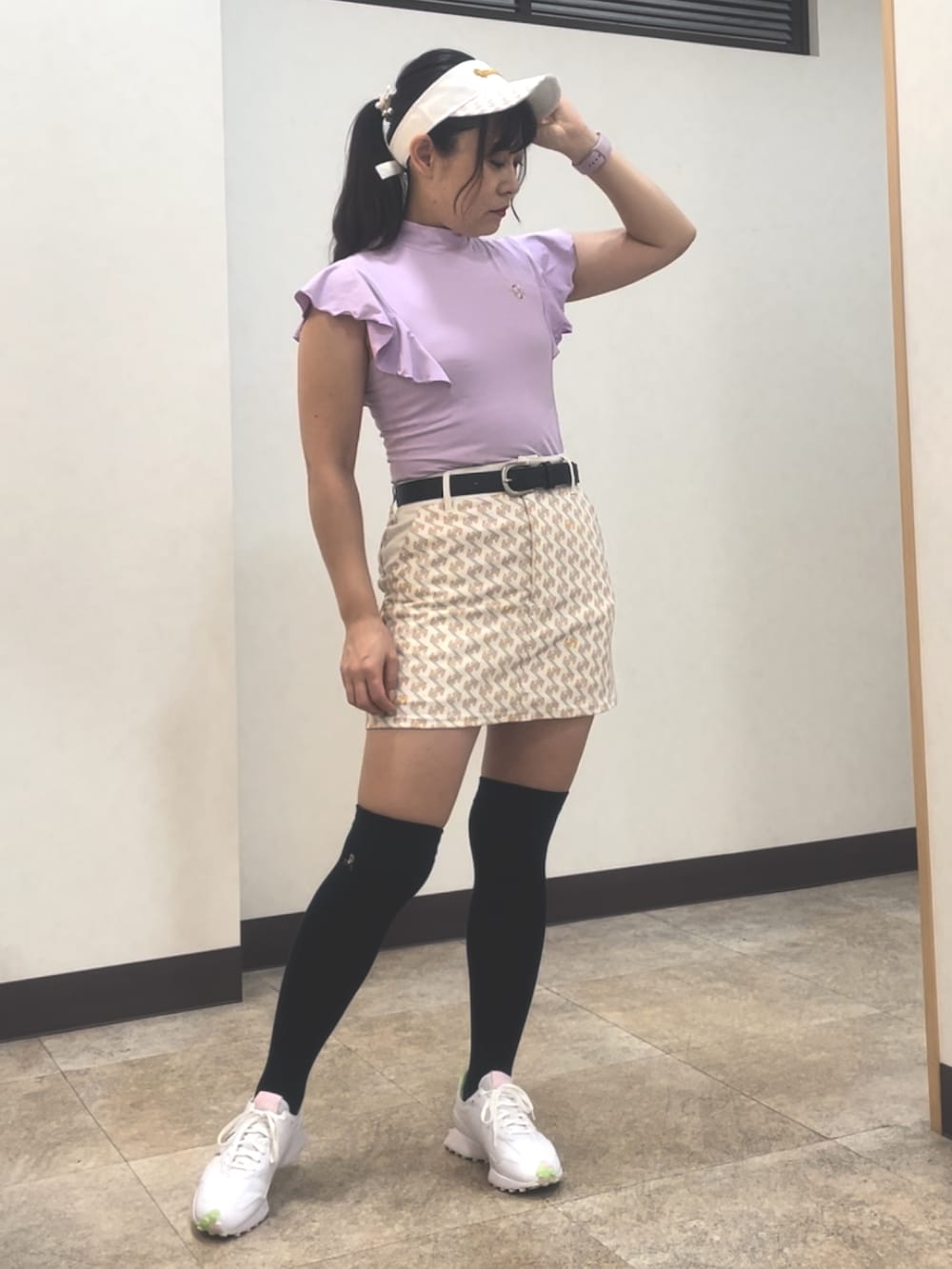 パープル系のトップス、ホワイト系のスカート、ホワイト系のスニーカーを着用したレディースの夏コーディネートの2枚目の写真