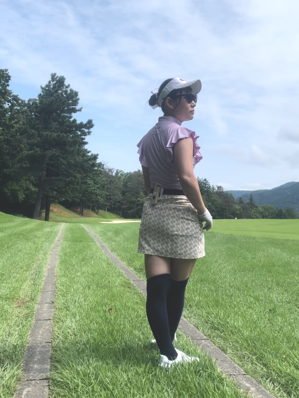 パープル系のトップス、ホワイト系のスカート、ホワイト系のスニーカーを着用したレディースの夏コーディネートの4枚目の写真