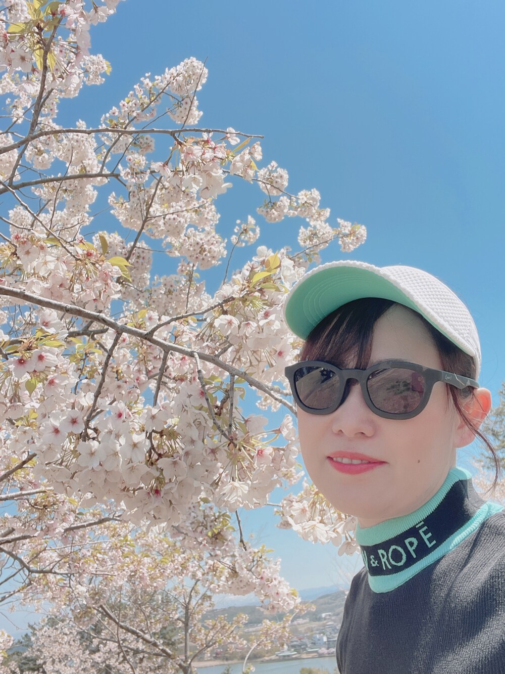 ブラック系のニット/セーター、ホワイト系のスカート、ホワイト系のスニーカーを着用したレディースの春コーディネートの5枚目の写真